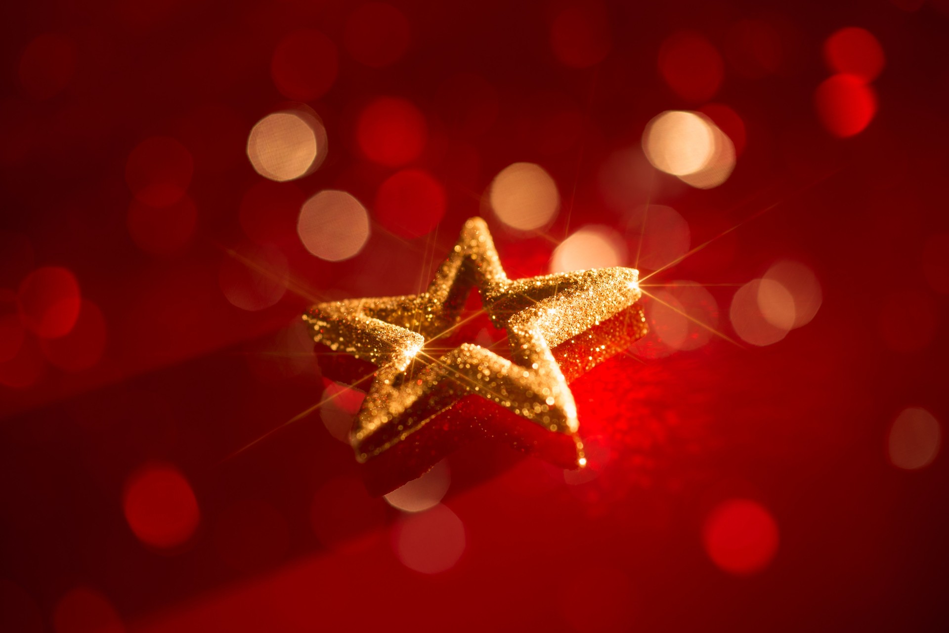 Golden Glitter Star on Vibrant Red Background with Glowing Bokeh Lights